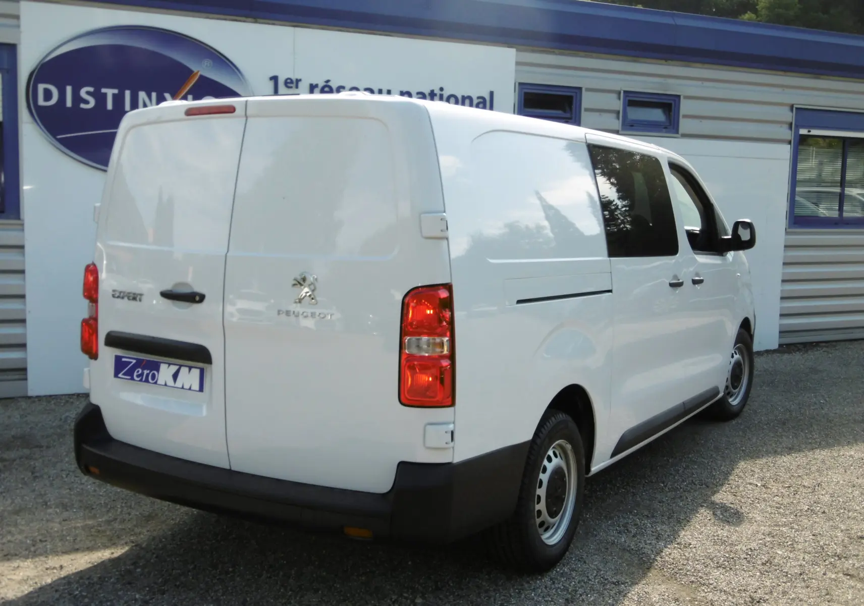 Vue 3/4 arrière droite d’un utilitaire Peugeot Expert blanc avec portes arrière battantes et vitres latérales teintées.