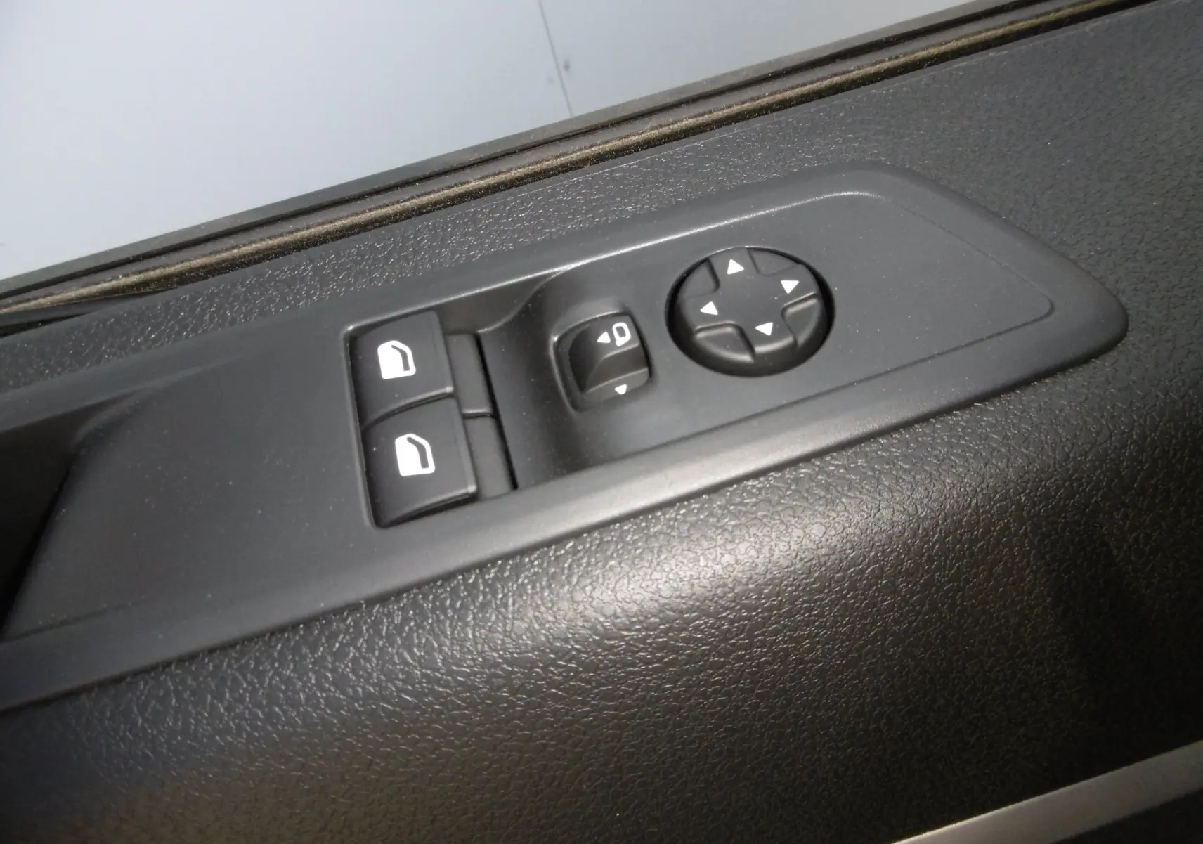 Gros plan sur les commandes de réglage des rétroviseurs et des vitres électriques côté conducteur du Peugeot Expert blanc 2023.