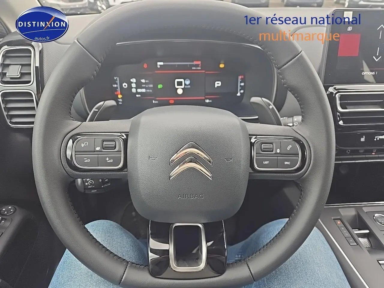 Vue rapprochée du volant cuir noir du Citroën C5 Aircross 2025 avec tableau de bord digital et commandes intégrées.