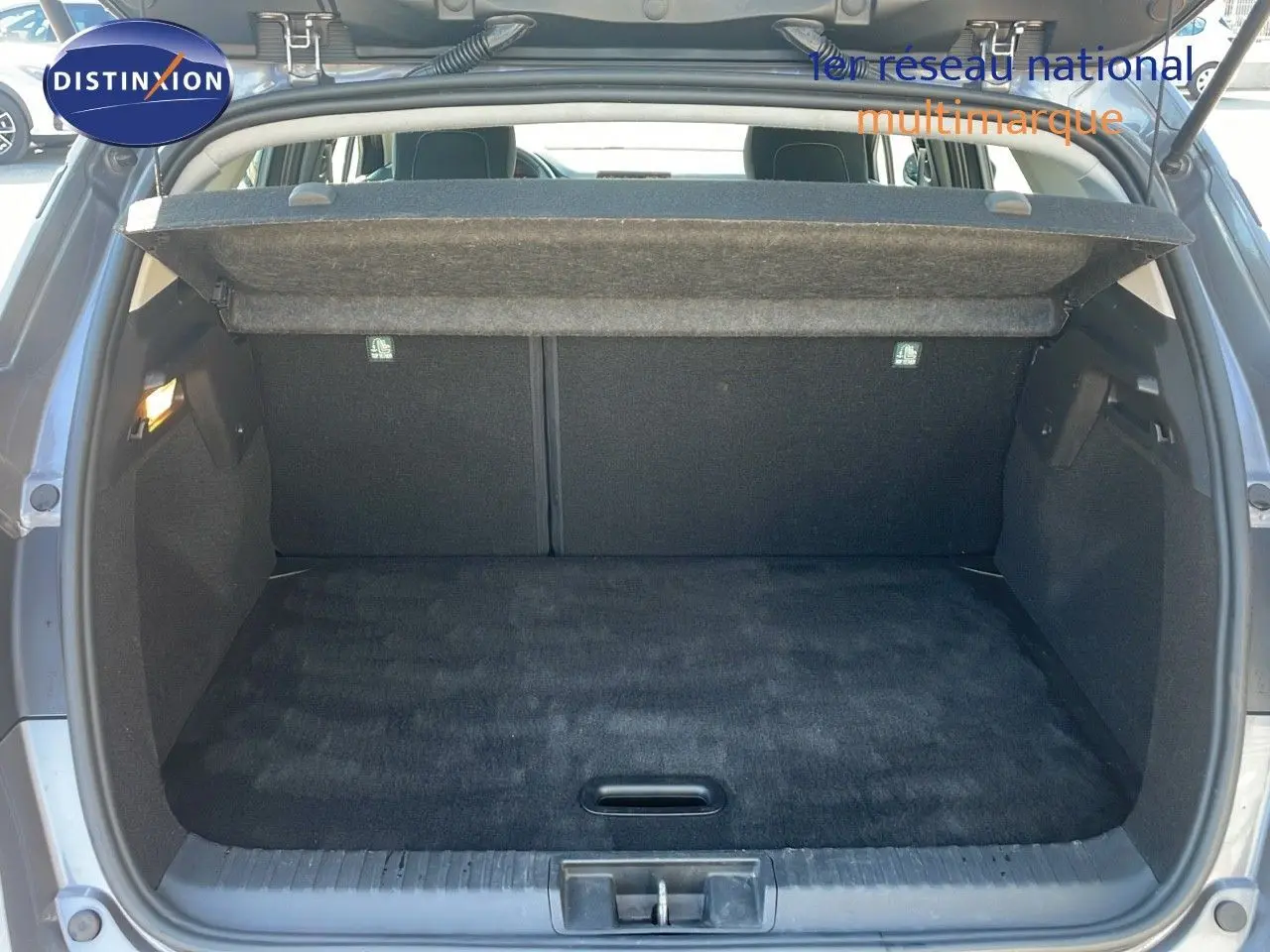Coffre ouvert vu de l'arrière du Renault Captur gris Cassiopée métal, montrant un espace de chargement propre et spacieux.