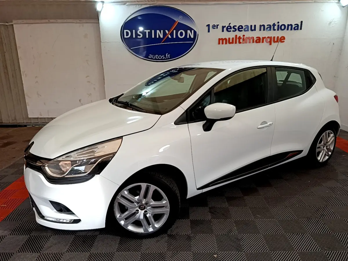 Renault Clio Business TCe 90 blanche vue de 3/4 avant droit, avec jantes alliage et feux LED, en intérieur showroom.