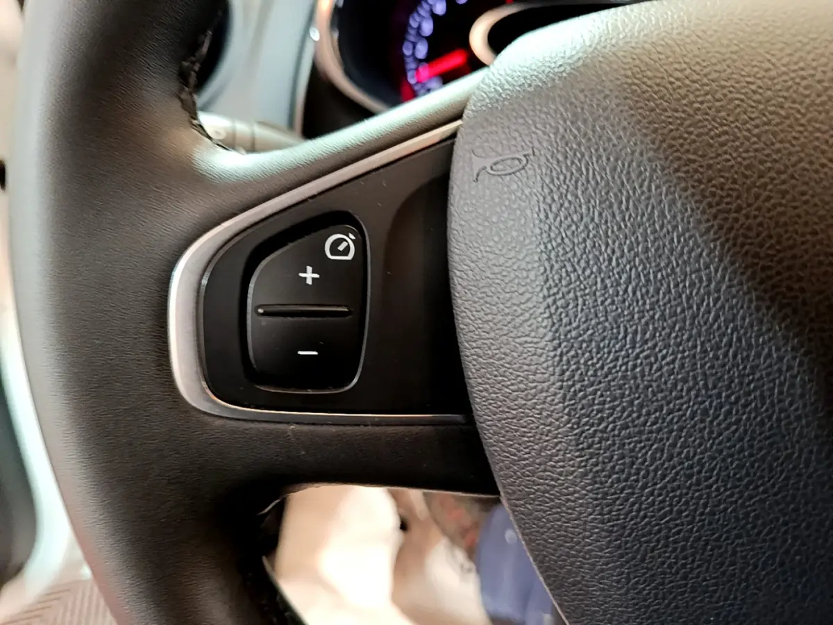 Gros plan sur les commandes de réglage du tableau de bord intégrées au volant cuir noir de la Renault Clio Business TCe 90.