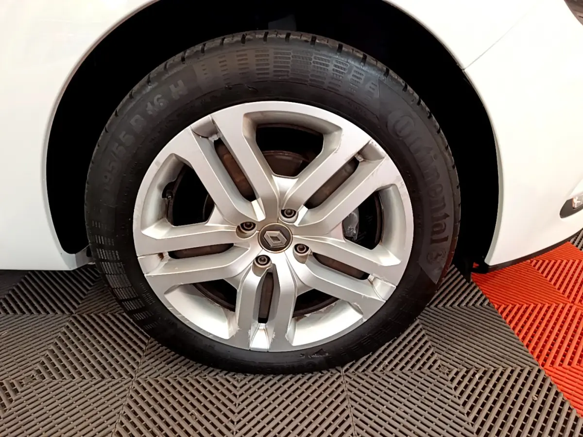 Gros plan sur la roue avant droite d'une Renault Clio Business blanche, jante alliage et pneu Continental visibles.