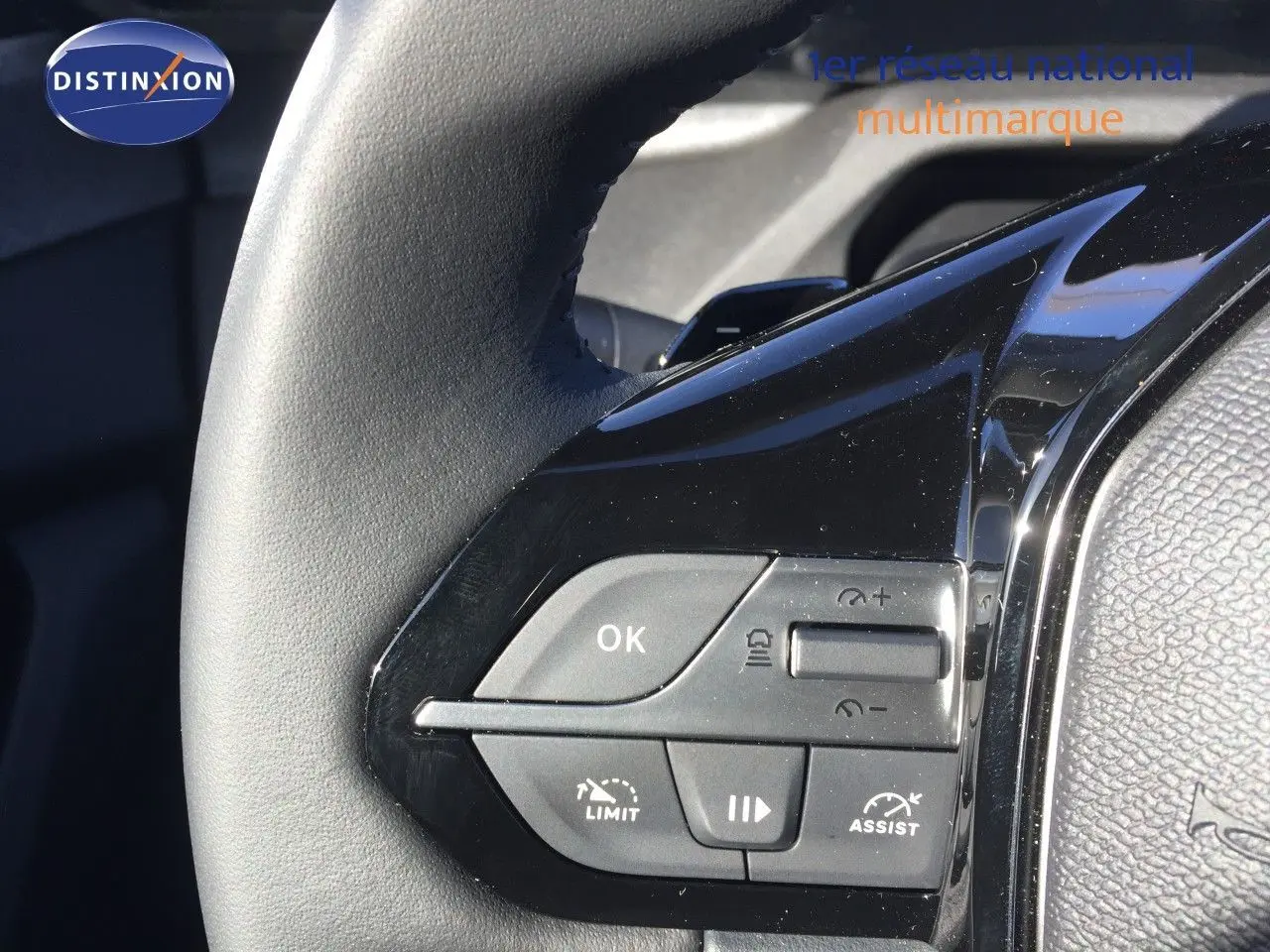 Gros plan sur les commandes au volant noir brillant de la Peugeot 308 gris Artense Hybrid 2025, côté gauche.