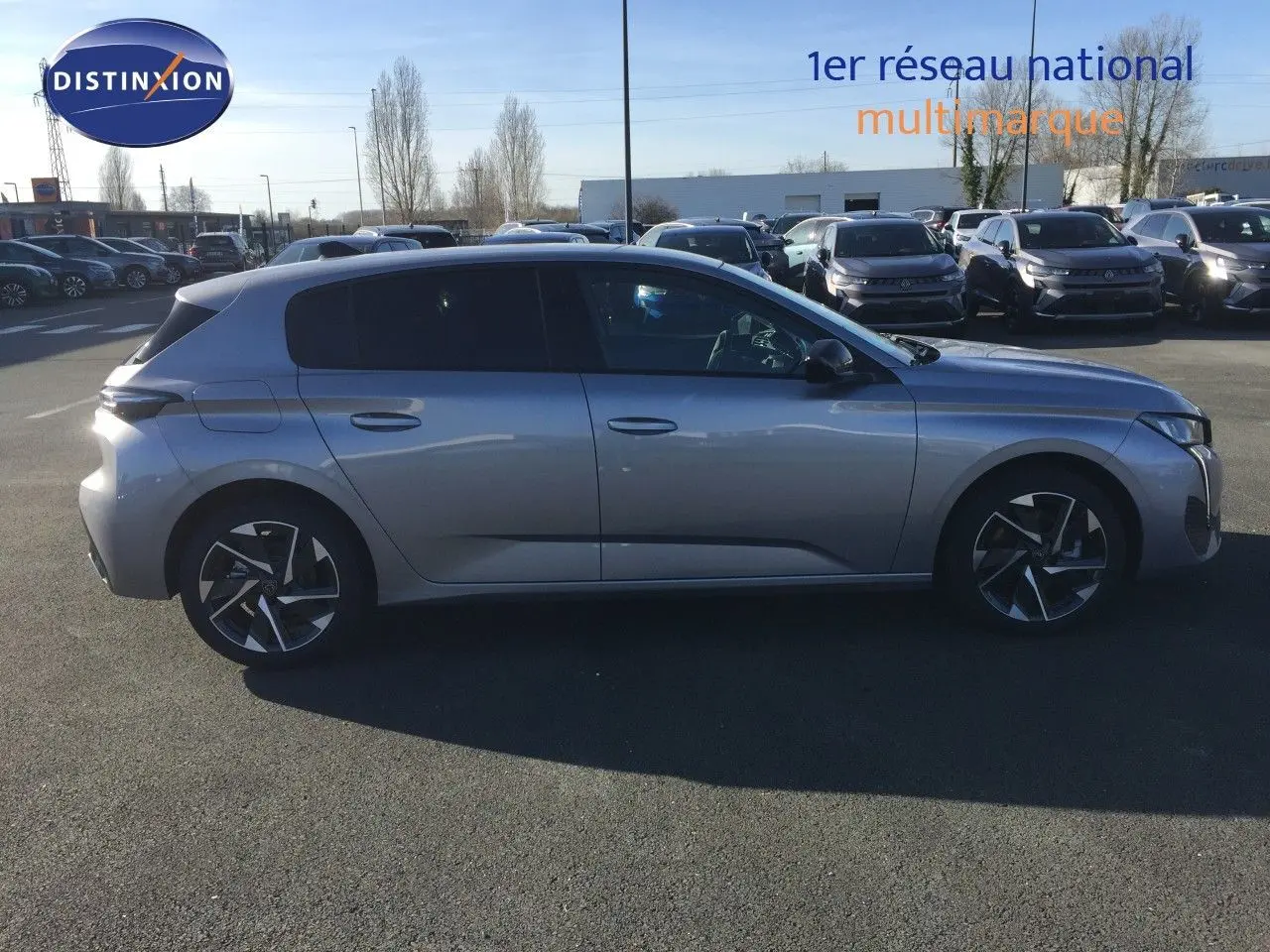 Peugeot 308 gris Artense métal vue de profil côté gauche sur parking avec jantes bi-ton et vitres teintées.