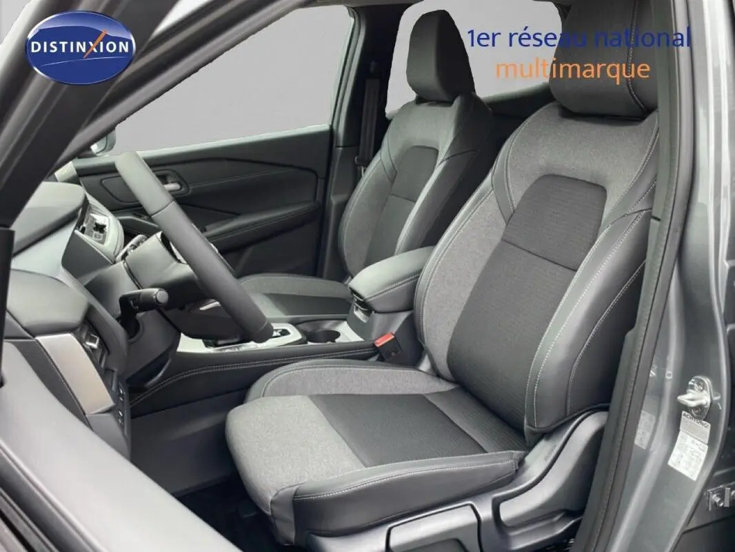 Vue intérieure côté conducteur du Nissan Qashqai gris 2025, mettant en valeur les sièges tissu et cuir ainsi que le volant multifonctions.