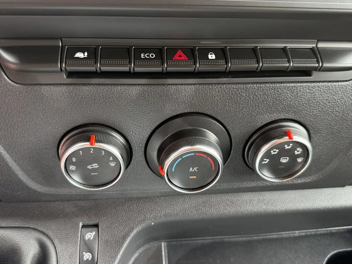 Gros plan sur les commandes de climatisation noires du tableau de bord du Renault Master blanc 2024.