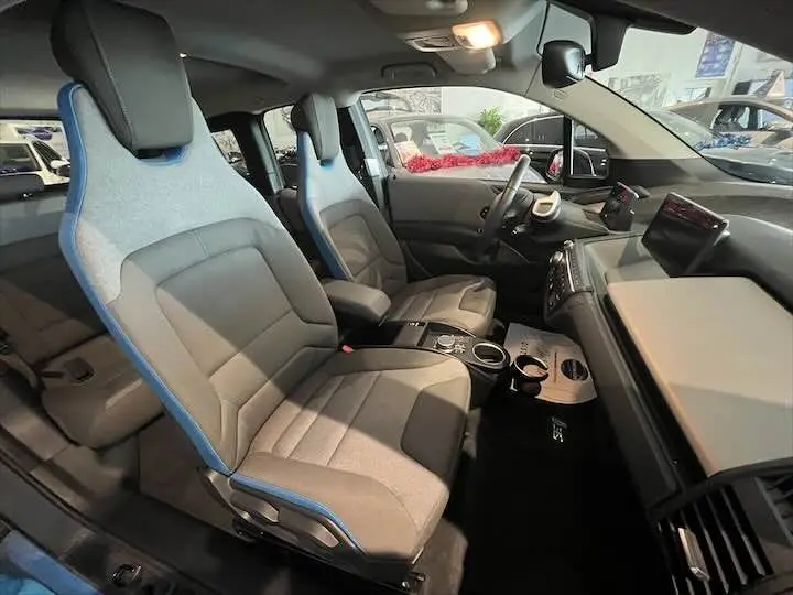 Intérieur de BMW i3 noir vu côté gauche, sièges gris bleuté avec détails modernes et tableau de bord épuré.