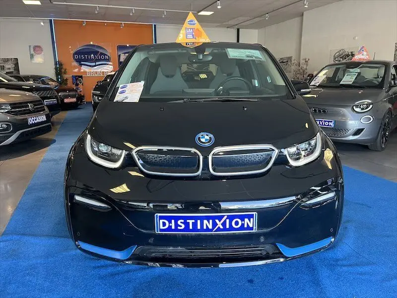 Vue frontale d'une BMW i3 noire électrique exposée en showroom avec plaque Distinxion visible.