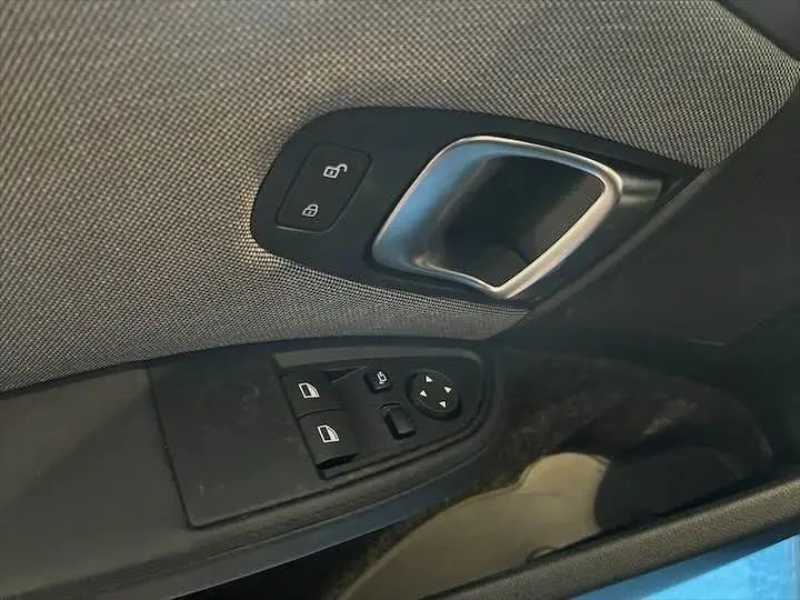 Poignée intérieure et commandes des vitres côté gauche d'une BMW i3 noire, finition Edition Windmill.