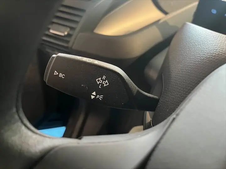 Le levier de commande noir du clignotant dans l'habitacle d'une BMW i3 2022, vue rapprochée côté gauche du volant.
