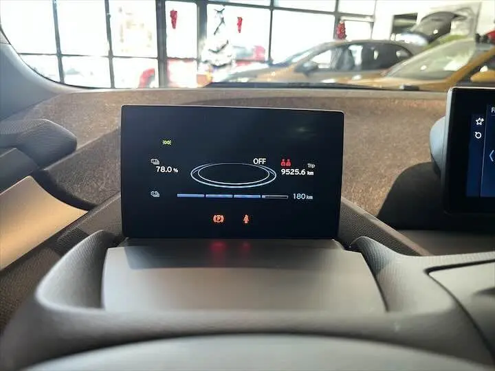 Écran central du tableau de bord de la BMW i3 noir, affichant l'autonomie et les informations de conduite.