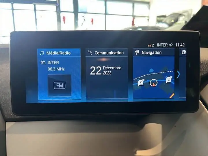 Écran central tactile de BMW i3 noir 2022 affichant radio FM, communication et navigation GPS.