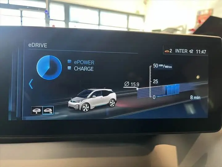 Affichage numérique montrant une BMW i3 blanche en vue latérale droite sur l'écran de bord du véhicule électrique.