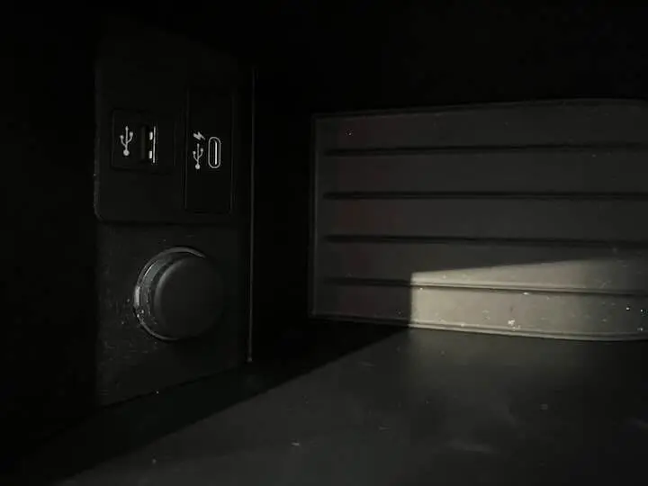 Prise USB et port USB-C dans l'habitacle sombre d'une BMW i3 noire, détail du tableau de bord côté gauche.
