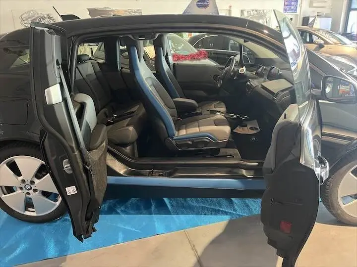 BMW i3 noire vue de profil droit avec portes ouvertes dévoilant l'intérieur aux sièges gris et bleu.