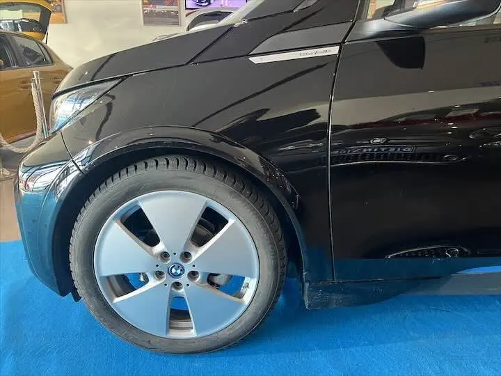 Gros plan sur la roue avant gauche et la portière noire d'une BMW i3 Edition Windmill, avec jante argentée distinctive.