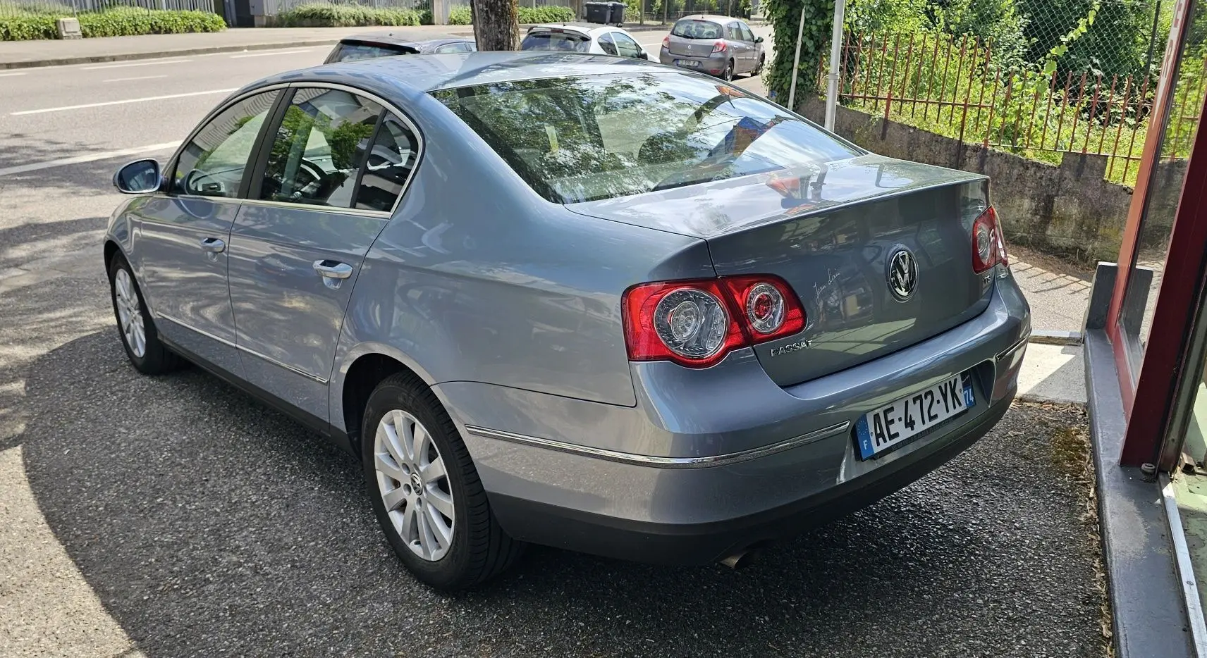 Vue 3/4 arrière droite d'une Volkswagen Passat bleu métallisé de 2009 avec feux arrière ronds et plaques françaises.