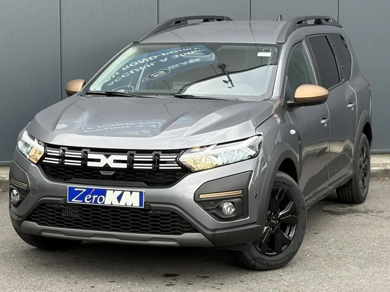 Vue 3/4 avant droite du Dacia Jogger Gris Schiste avec jantes noires et rétroviseurs couleur bronze.