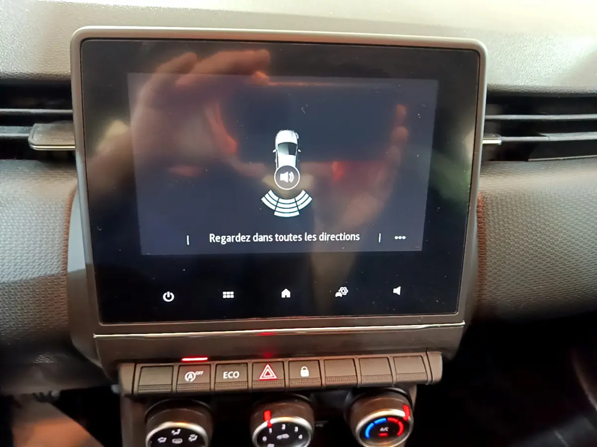 Écran tactile central affichant l'alerte de stationnement dans l'habitacle d'une Renault Clio Business blanc.