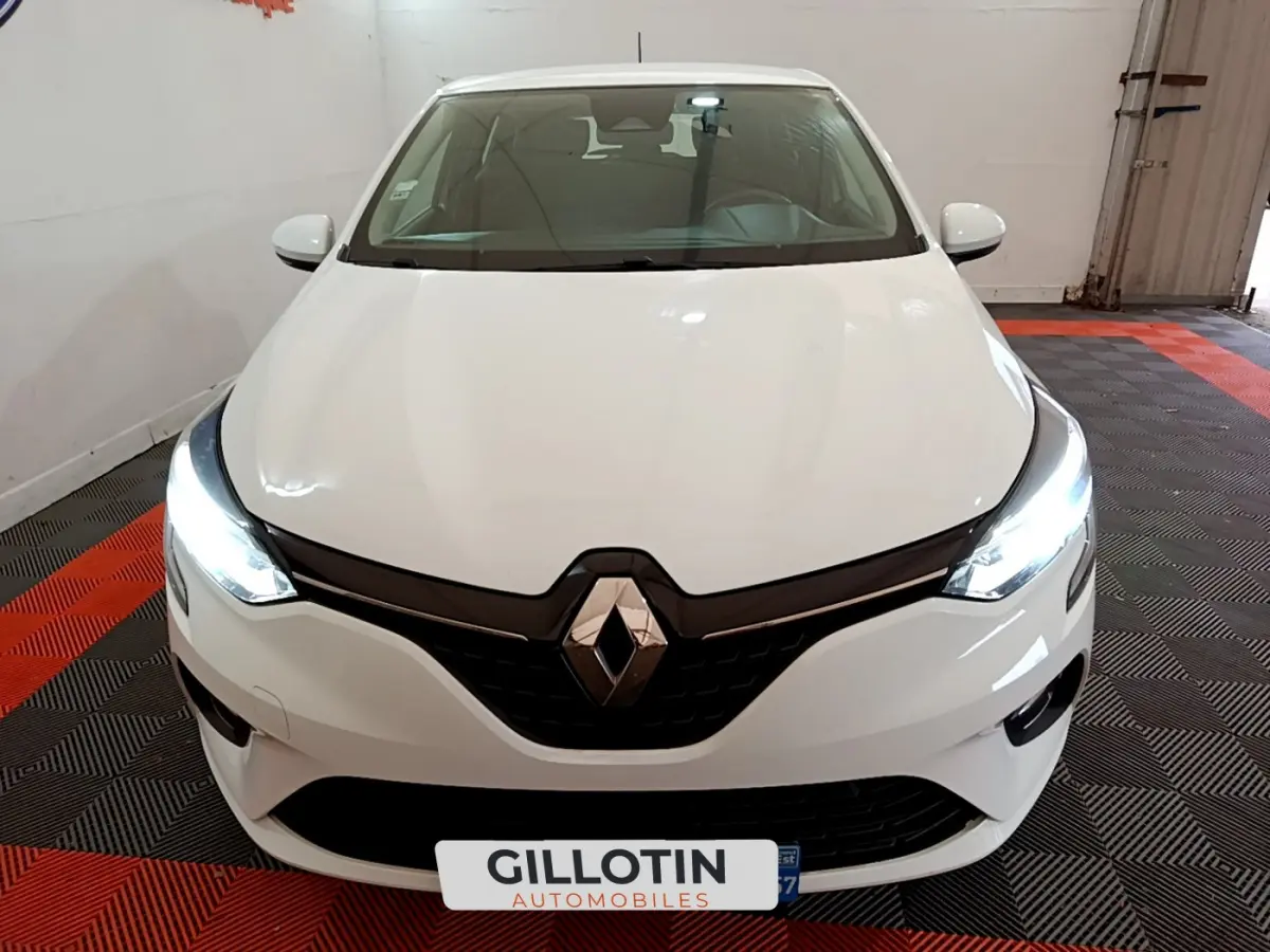Vue avant d'une Renault Clio Business Blue dCi 85 blanche avec phares LED allumés dans un garage.