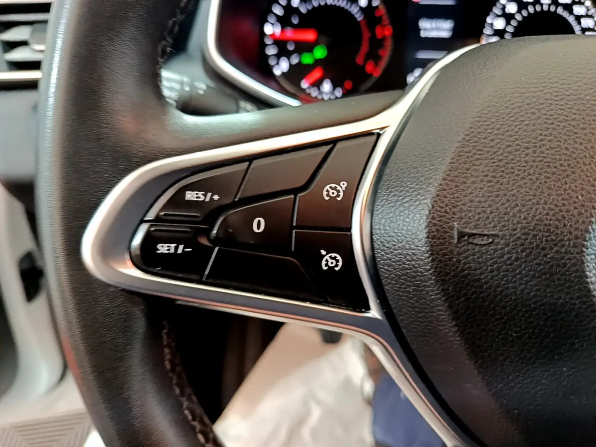 Gros plan sur les commandes noires du régulateur de vitesse à gauche du volant cuir noir de la Renault Clio Business 2020.