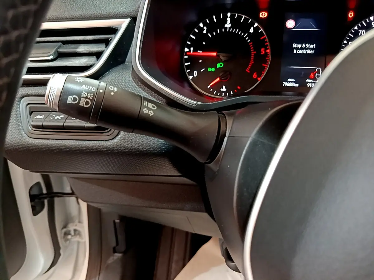Gros plan sur la manette des phares et clignotants côté gauche du tableau de bord d'une Renault Clio Business Blue dCi blanche de 2020.