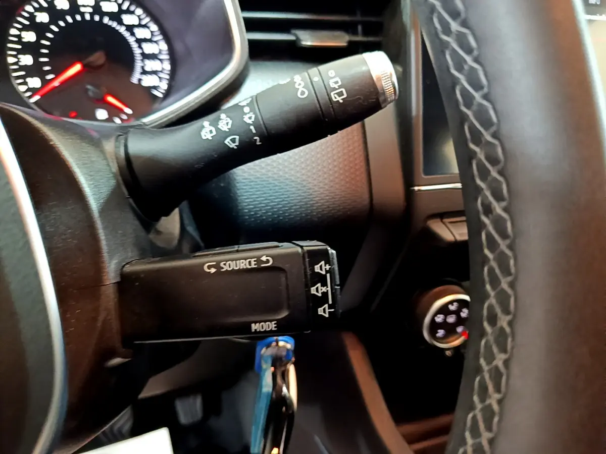 Gros plan sur la commande multimédia et le commodo d'essuie-glace du tableau de bord noir de la Renault Clio Business.