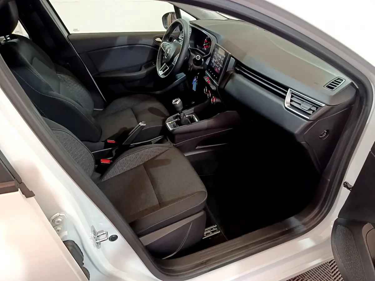 Intérieur de la Renault Clio Business Blue dCi 85 blanc, vue côté conducteur montrant sièges et tableau de bord moderne.