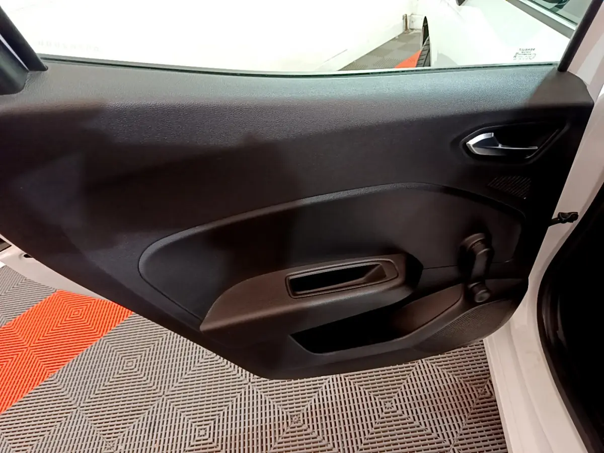 Vue intérieure de la porte côté droit noire d'une Renault Clio Business blanche avec poignée et manivelle de vitre.