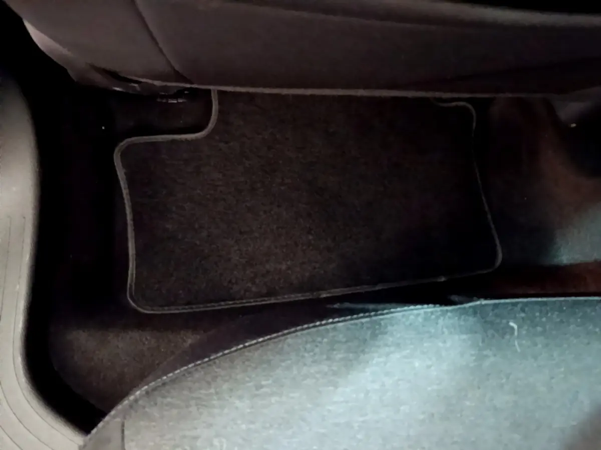 Vue rapprochée du tapis de sol noir côté passager arrière d'une Renault Clio Business blanche de 2020.