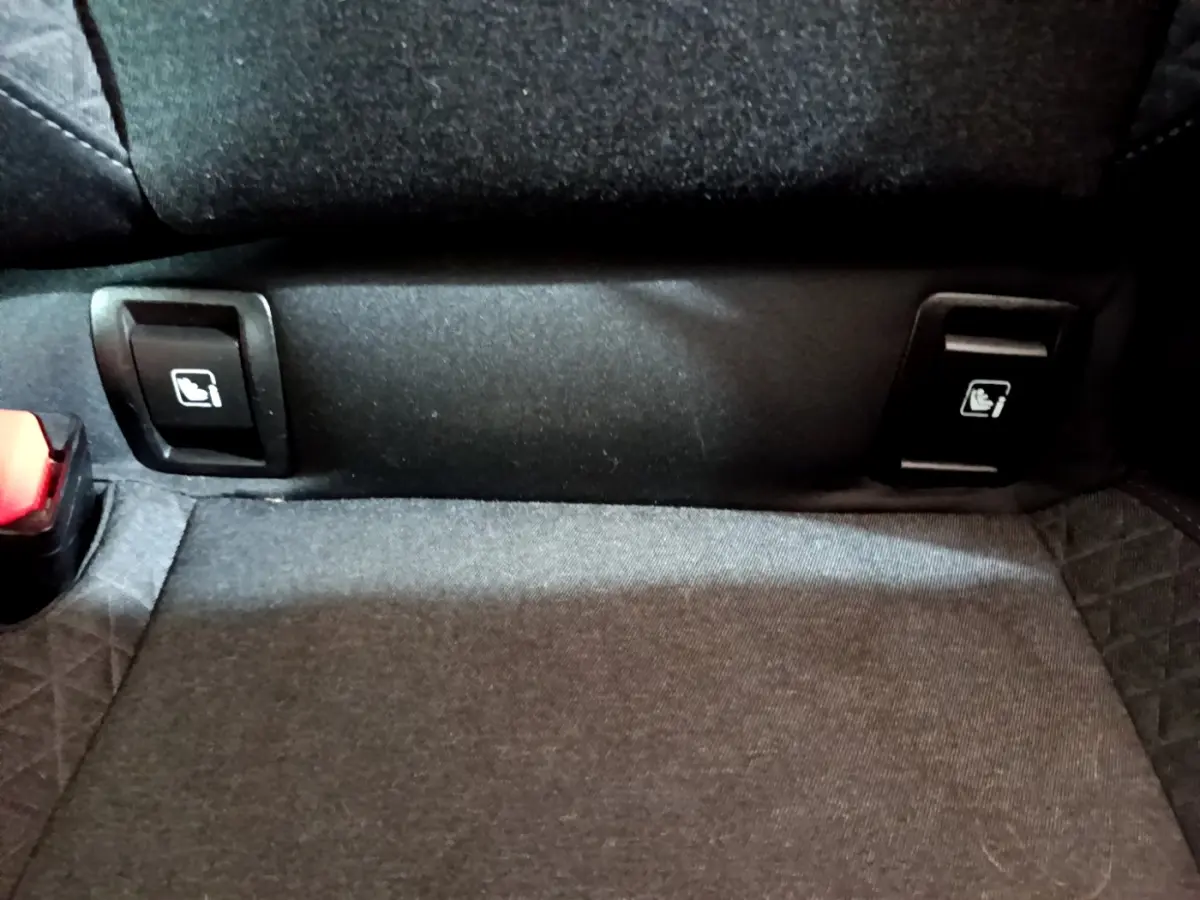 Gros plan sur les commandes de rabattement des sièges arrière noirs de la Renault Clio Business Blue dCi 85 blanche.