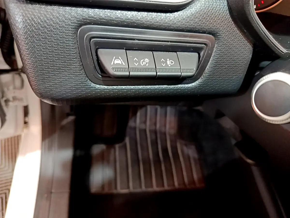 Gros plan sur les commandes d'assistance à la conduite noires dans l'habitacle de la Renault Clio Business Blue dCi 85 blanche.