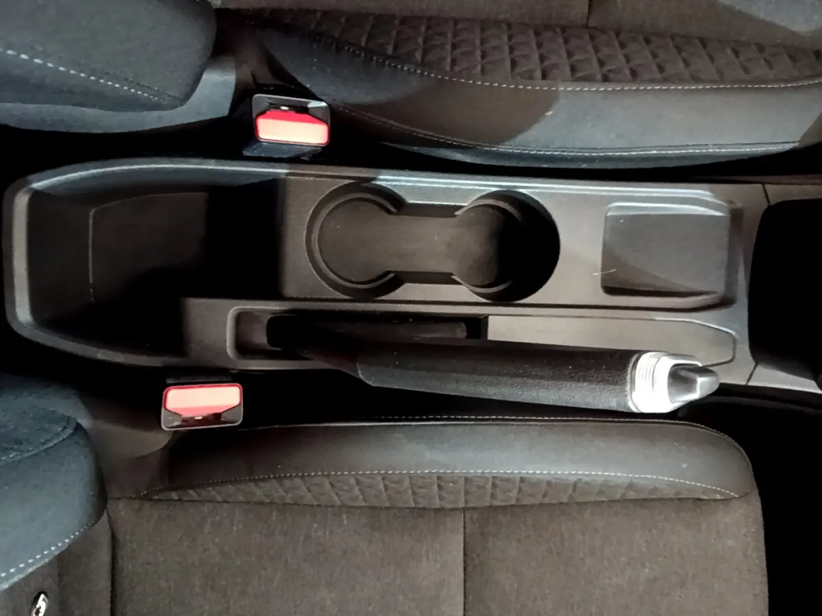 Vue plongeante sur la console centrale noire de la Renault Clio Business Blue dCi 85 avec frein à main et porte-gobelets.