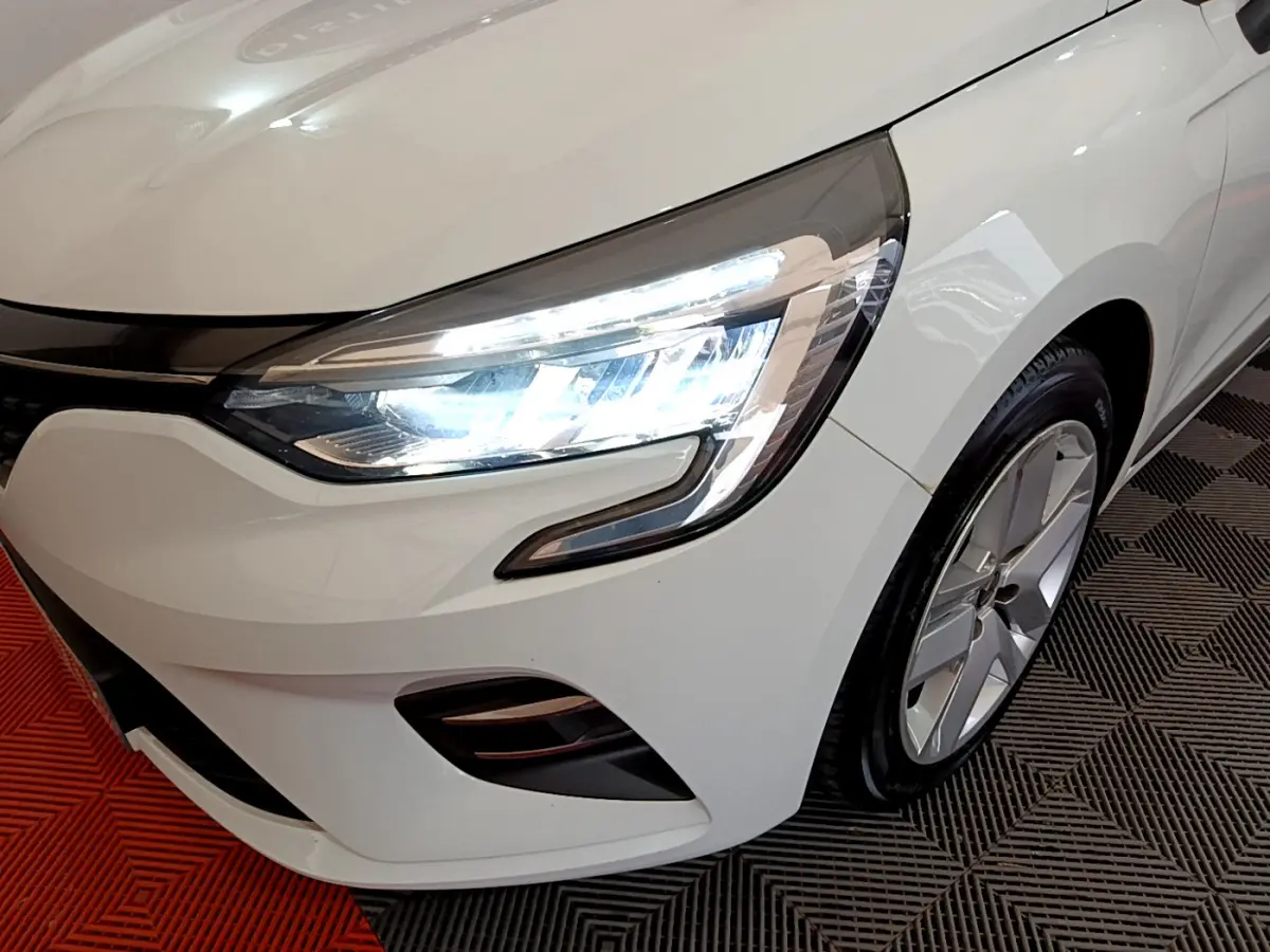 Gros plan sur l'avant droit blanc d'une Renault Clio 2020 Business Blue dCi avec phares LED allumés et jante alliage.