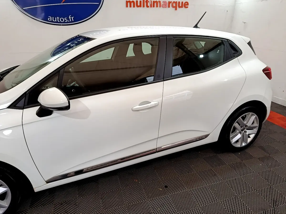 Profil côté gauche d'une Renault Clio Business Blue dCi 85 blanche, avec jantes alliage et poignées de porte assorties.