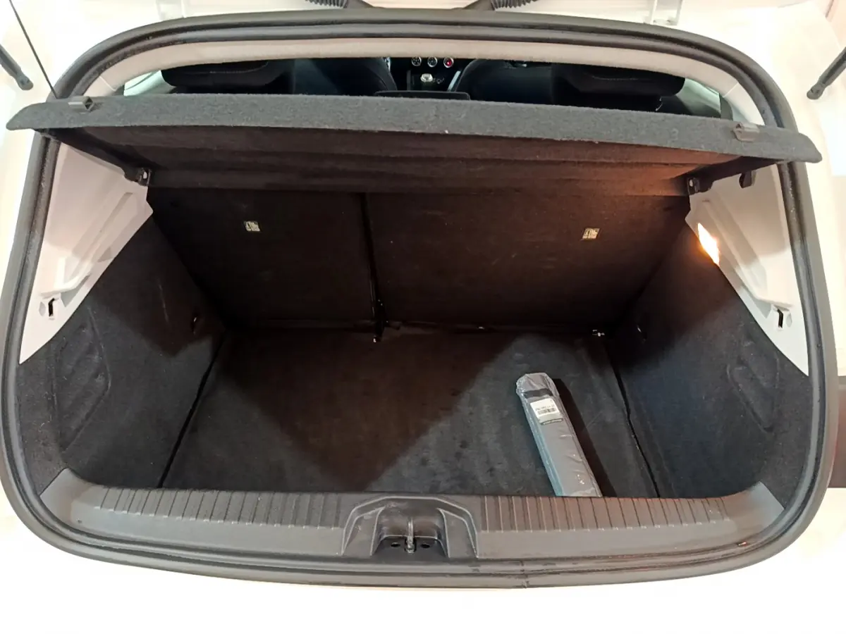 Coffre ouvert d'une Renault Clio Business Blue dCi 85 blanche, vue arrière montrant l'espace de chargement vide avec une petite trousse.