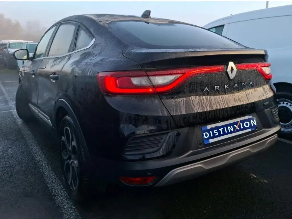 Vue 3/4 arrière gauche d'un Renault Arkana noir métal 2023 avec feux arrière allumés et logo visible.