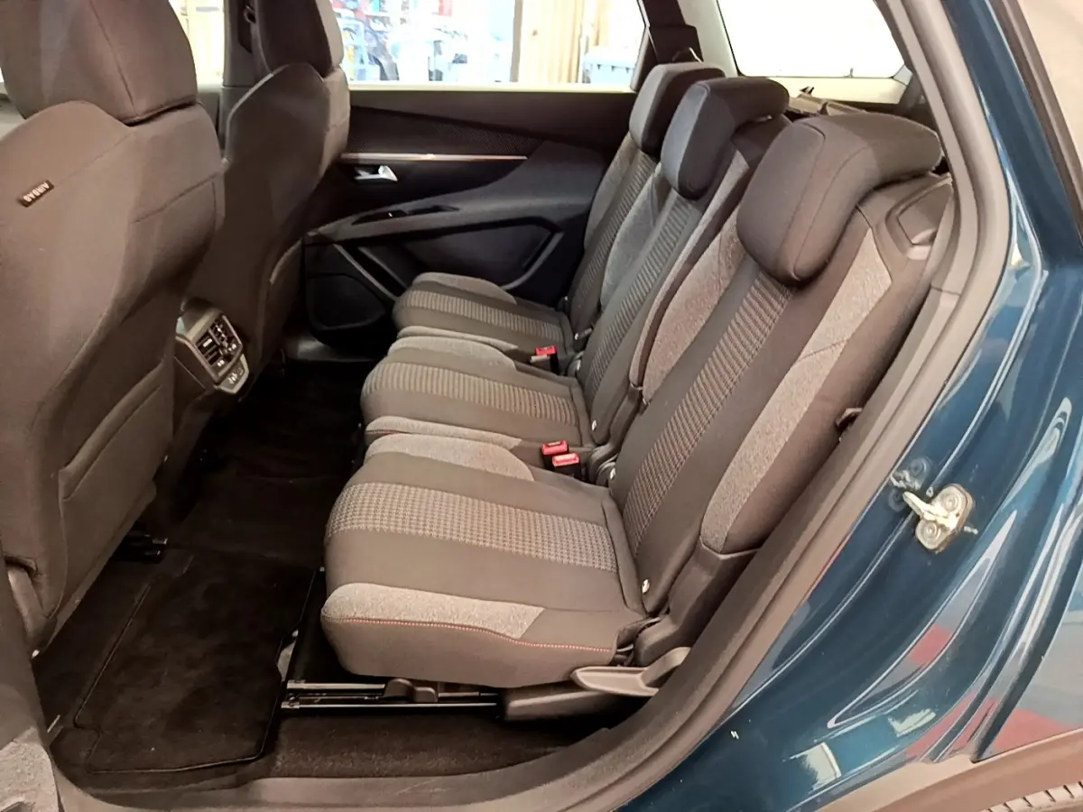 Vue latérale des sièges arrière gris du Peugeot 5008 bleu, montrant les trois places individuelles et l’espace intérieur.