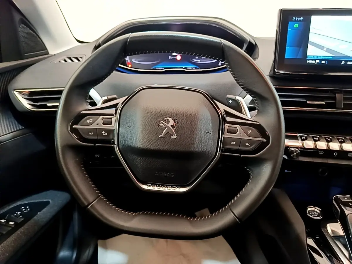 Volant cuir multifonctions Peugeot 5008 2021 vu de face avec tableau de bord numérique et écran tactile bleu.