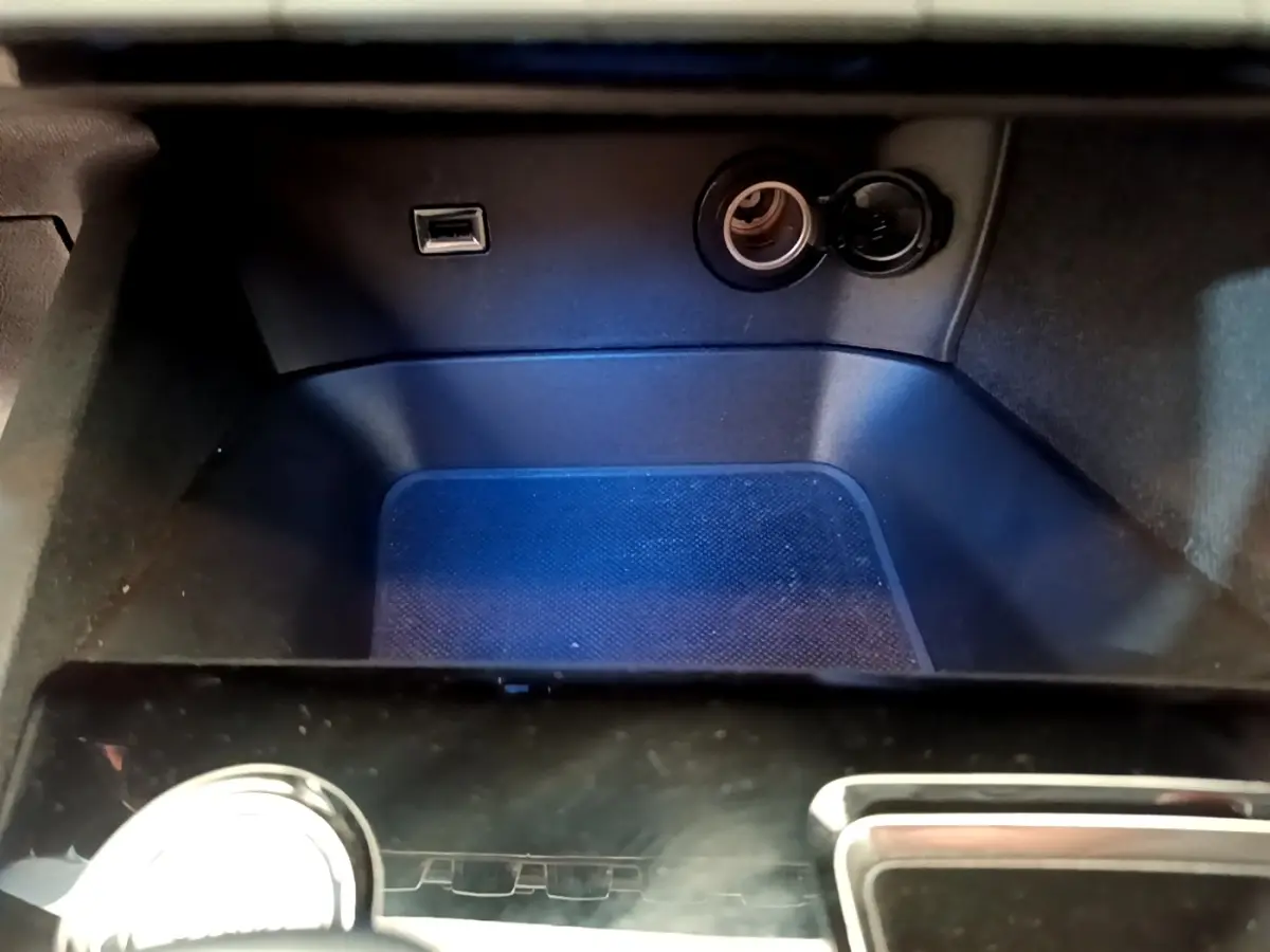 Gros plan sur la prise USB et l’allume-cigare dans le rangement avant noir du Peugeot 5008 bleu de 2021.