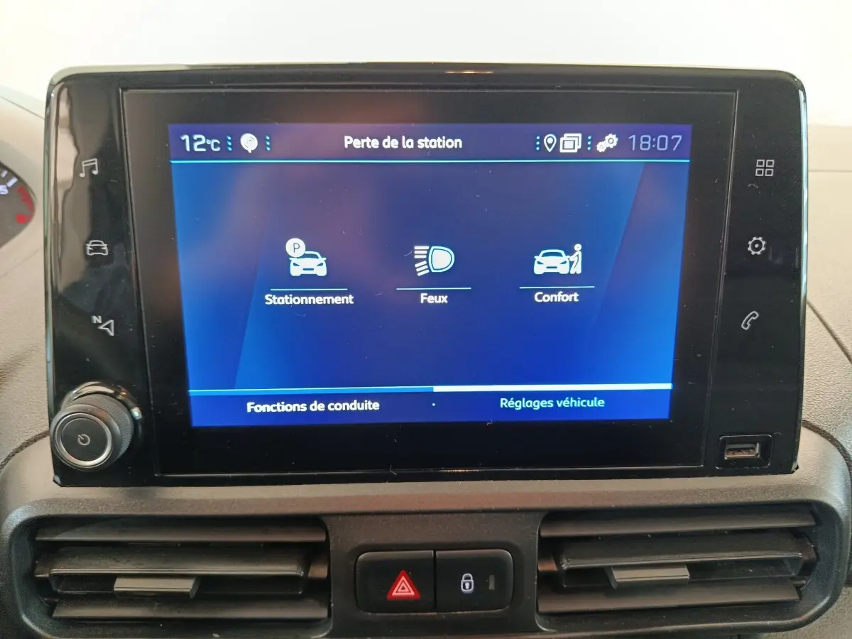 Écran tactile central du Peugeot Partner blanc 2021 affichant les réglages de stationnement, feux et confort.