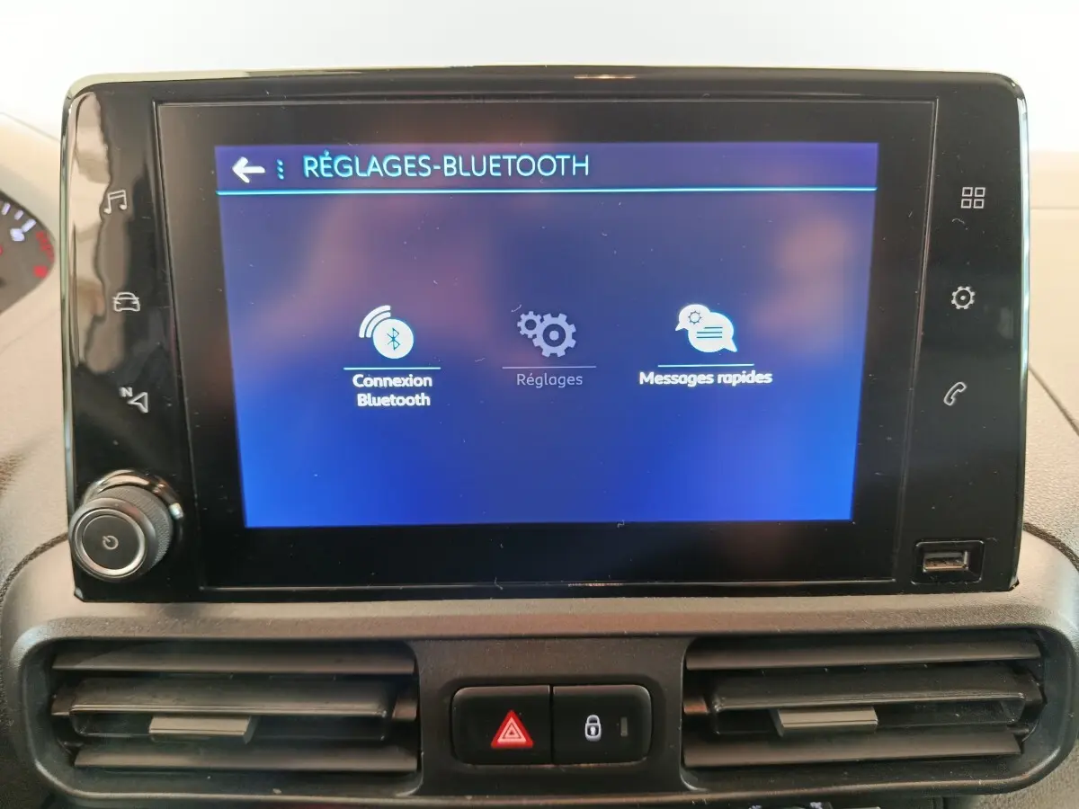 Vue rapprochée de l'écran tactile central du Peugeot Partner blanc 2021 affichant le menu réglages Bluetooth.