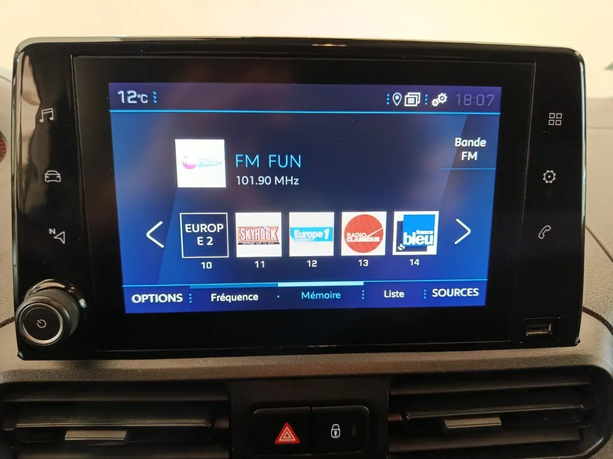 Écran tactile central du Peugeot Partner blanc 2021 affichant les stations radio FM avec commandes autour.
