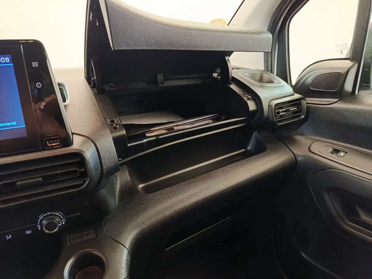 Intérieur du Peugeot Partner 2021, vue côté passager sur la boîte à gants ouverte et la console noire.