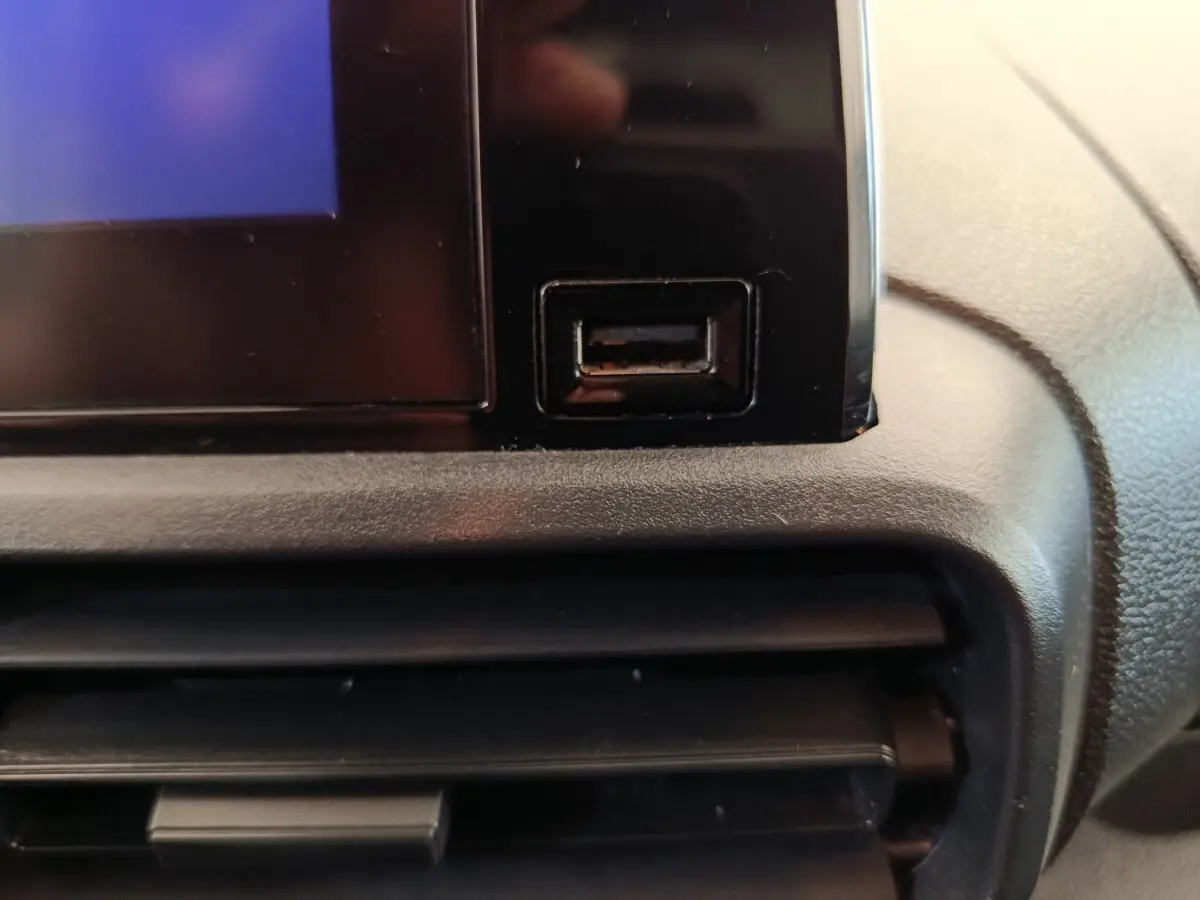 Gros plan sur la prise USB noire intégrée à la console centrale du Peugeot Partner 2021, intérieur gris.