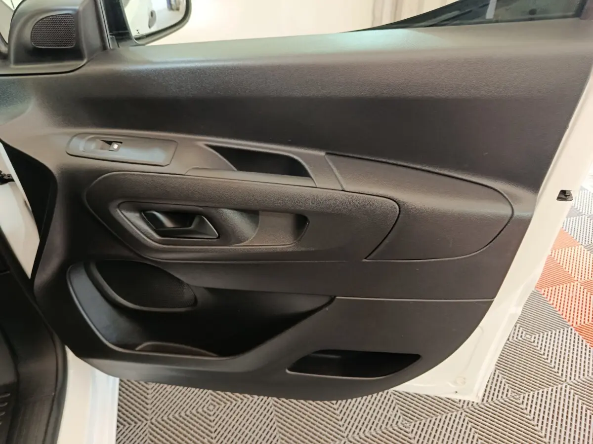 Vue rapprochée de la porte avant gauche noire intérieure du Peugeot Partner blanc, avec poignée et commande de vitre.
