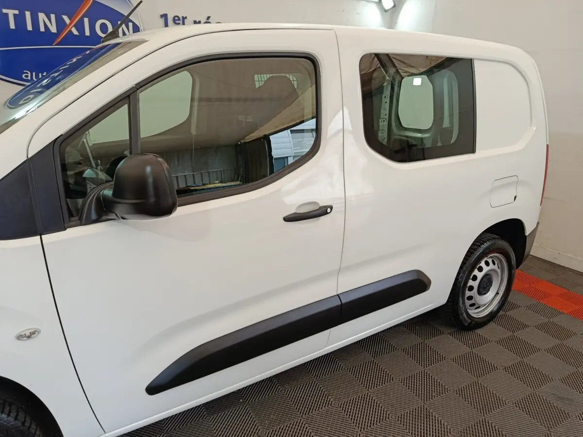 Vue de profil côté gauche d'un Peugeot Partner blanc 2021 avec porte latérale coulissante et jantes acier.