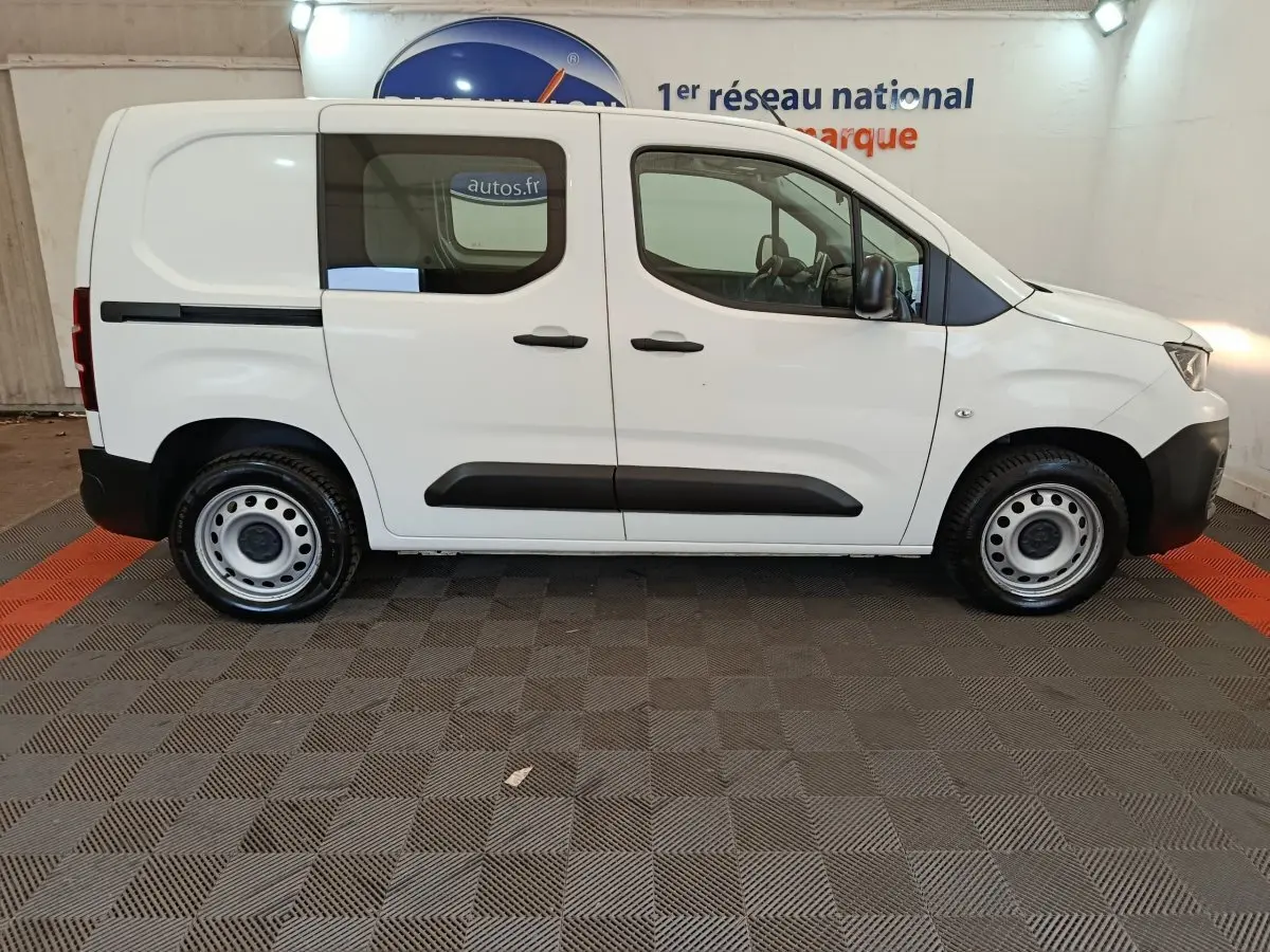 Vue de profil côté droit d’un utilitaire Peugeot Partner blanc avec vitres latérales et jantes acier.