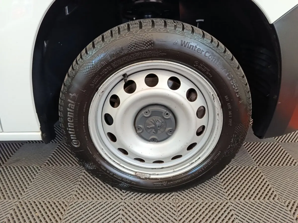 Gros plan sur la roue avant gauche blanche en jante acier du Peugeot Partner blanc, avec pneu hiver Continental visible.